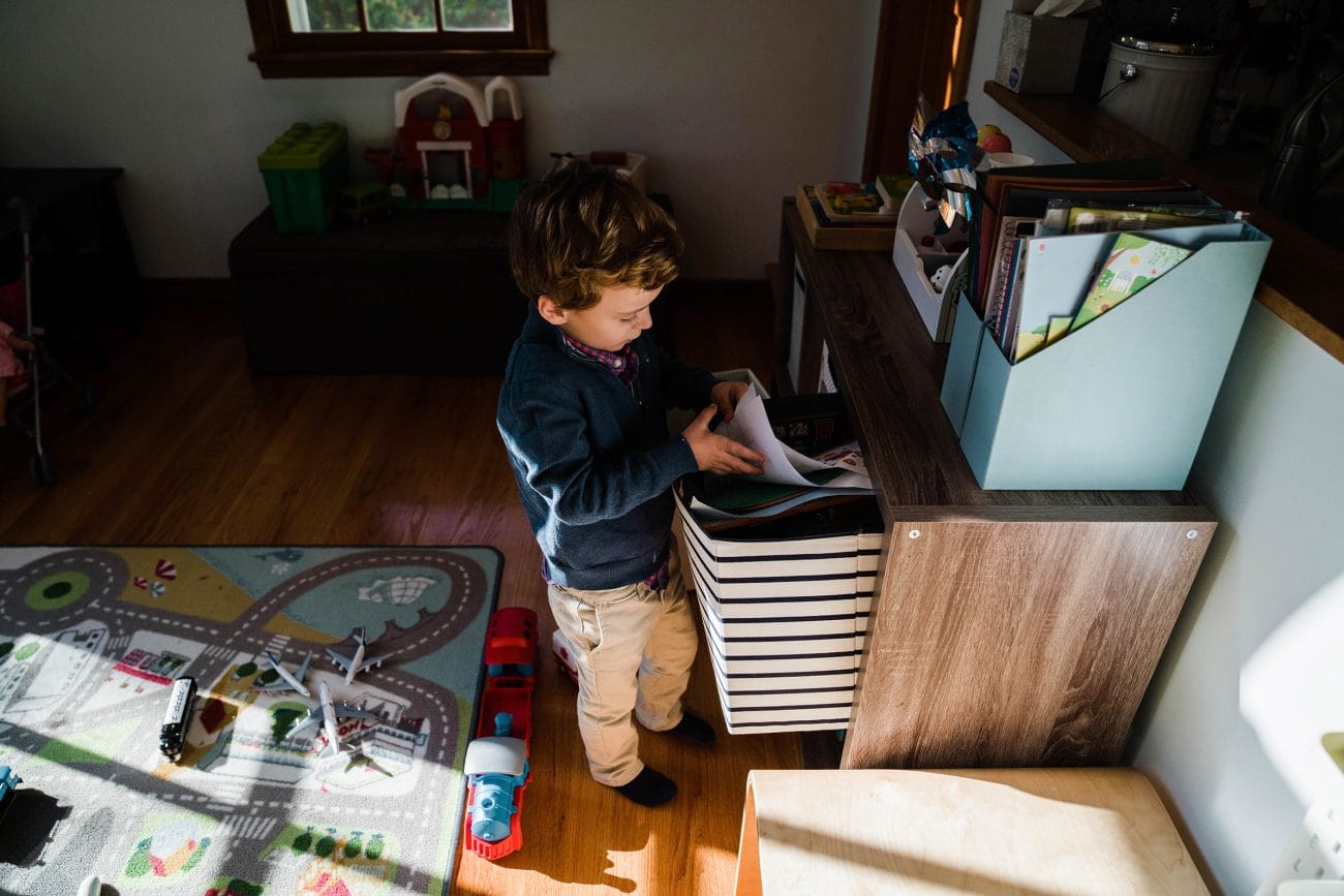 A documentary photograph of a boy getting out paper to draw on during an in home family session in Boston