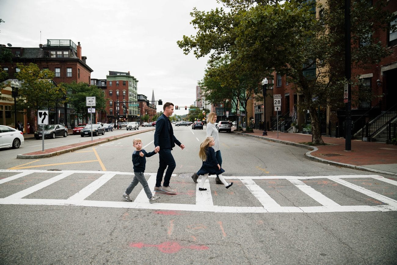 A documentary photograph of a family crossing the street during their in home family session in Boston