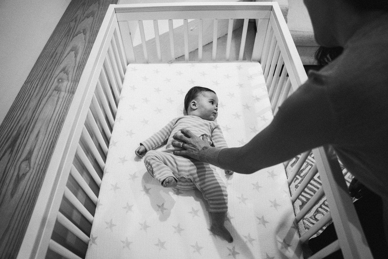 A documentary photograph of a mother putting her daughter down for a nap during an in home family session in Boston
