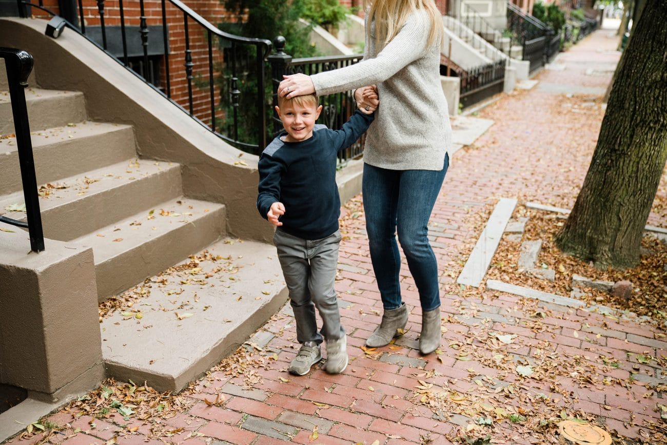 A documentary photograph of a mother and son on the sidewalk during an in home family session in Boston