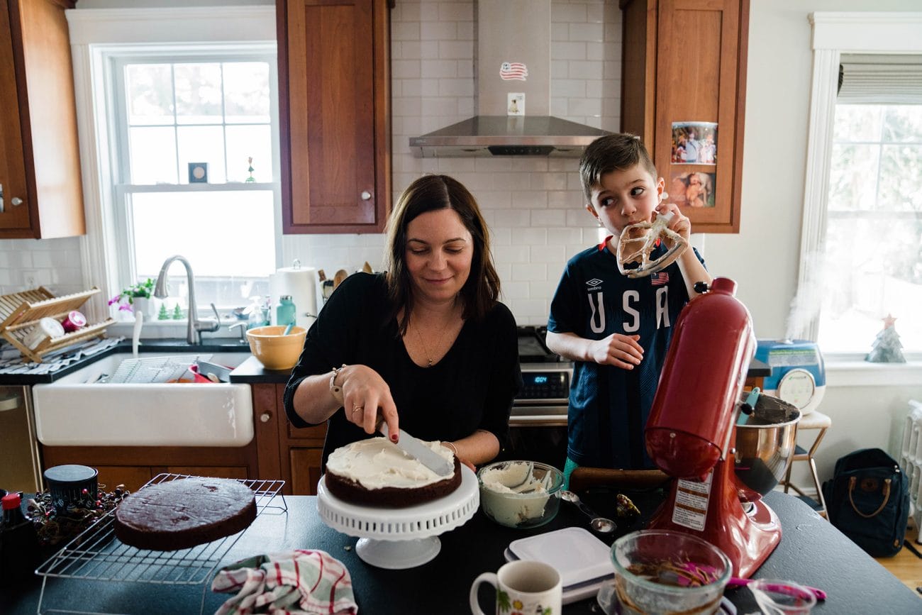 A documentary photograph of a boy licking frosting of the whisk during an in home family session in Boston