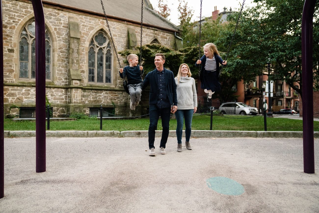 A documentary photograph of a family playing at the playground during a day in the life photo session in Boston