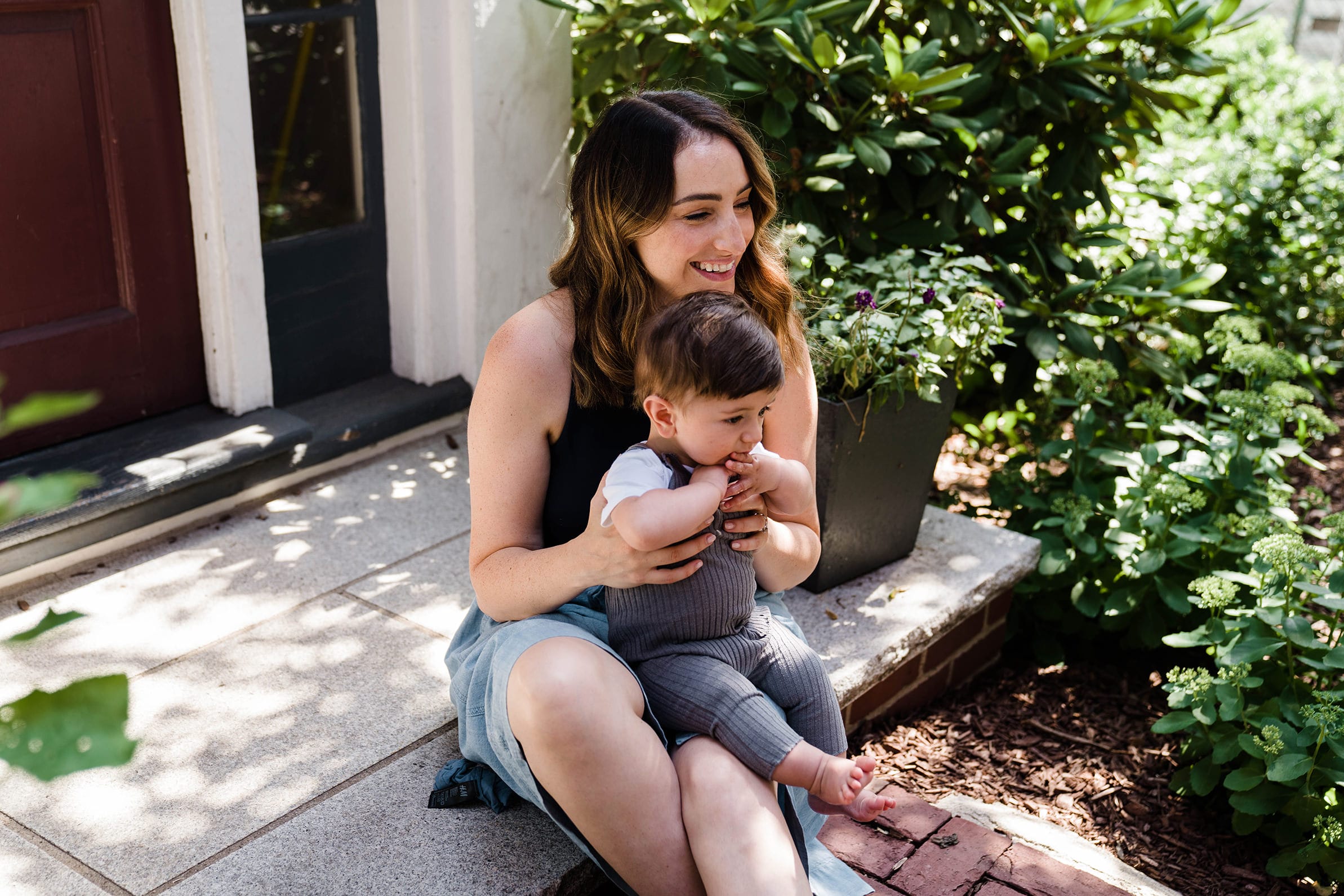 A best of Boston family photograph of a mom cuddling sitting on the porch with her baby during an in home family session in Boston