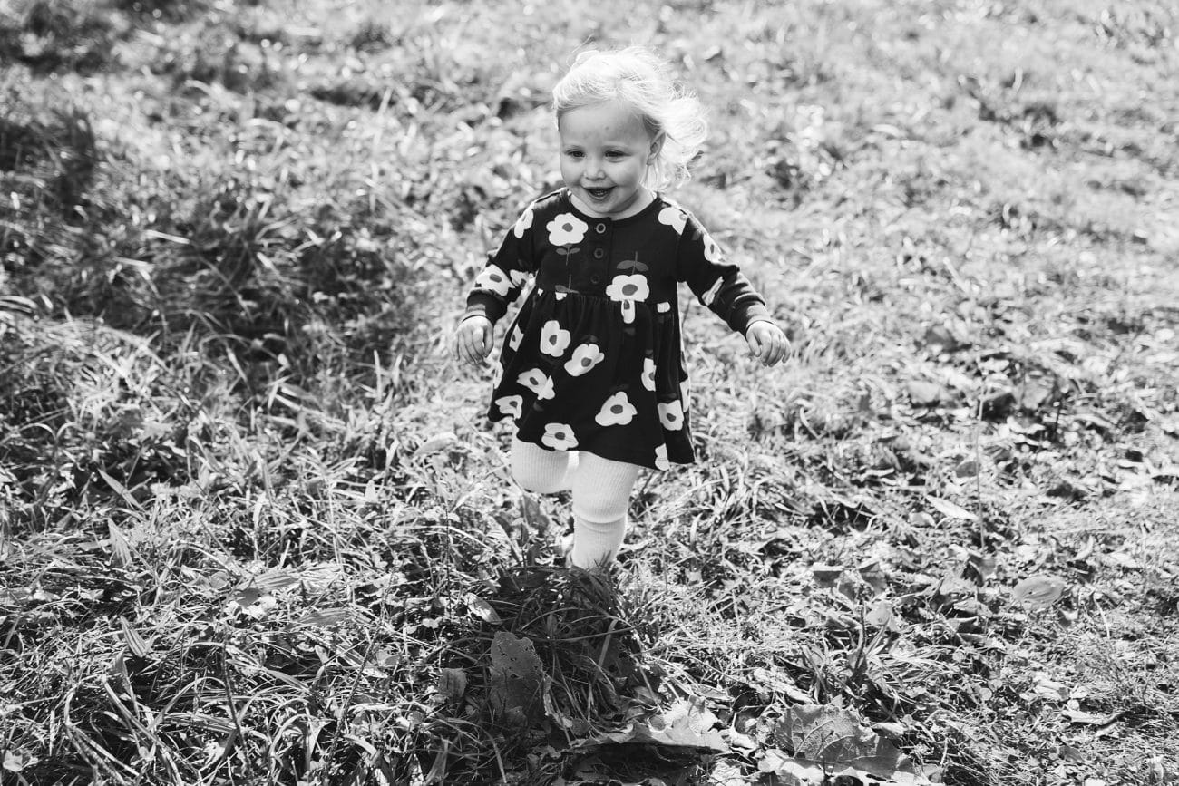A documentary photograph of girl running in the grass during a family session in Boston