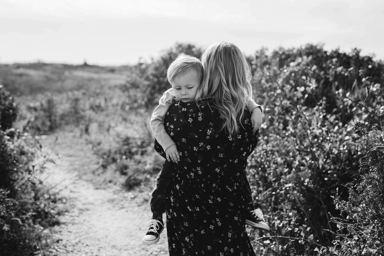 A documentary photograph of a mom carrying her son during a family session in Boston