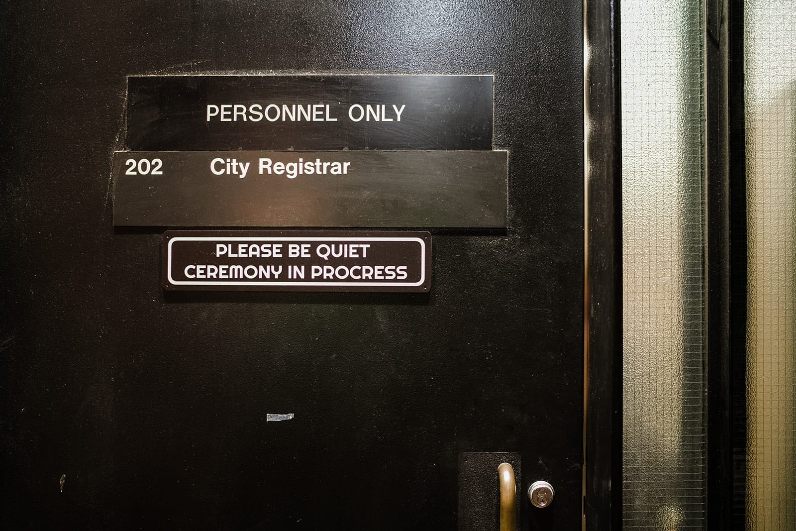 A documentary photograph of a door at Boston City Hall during a marriage ceremony.