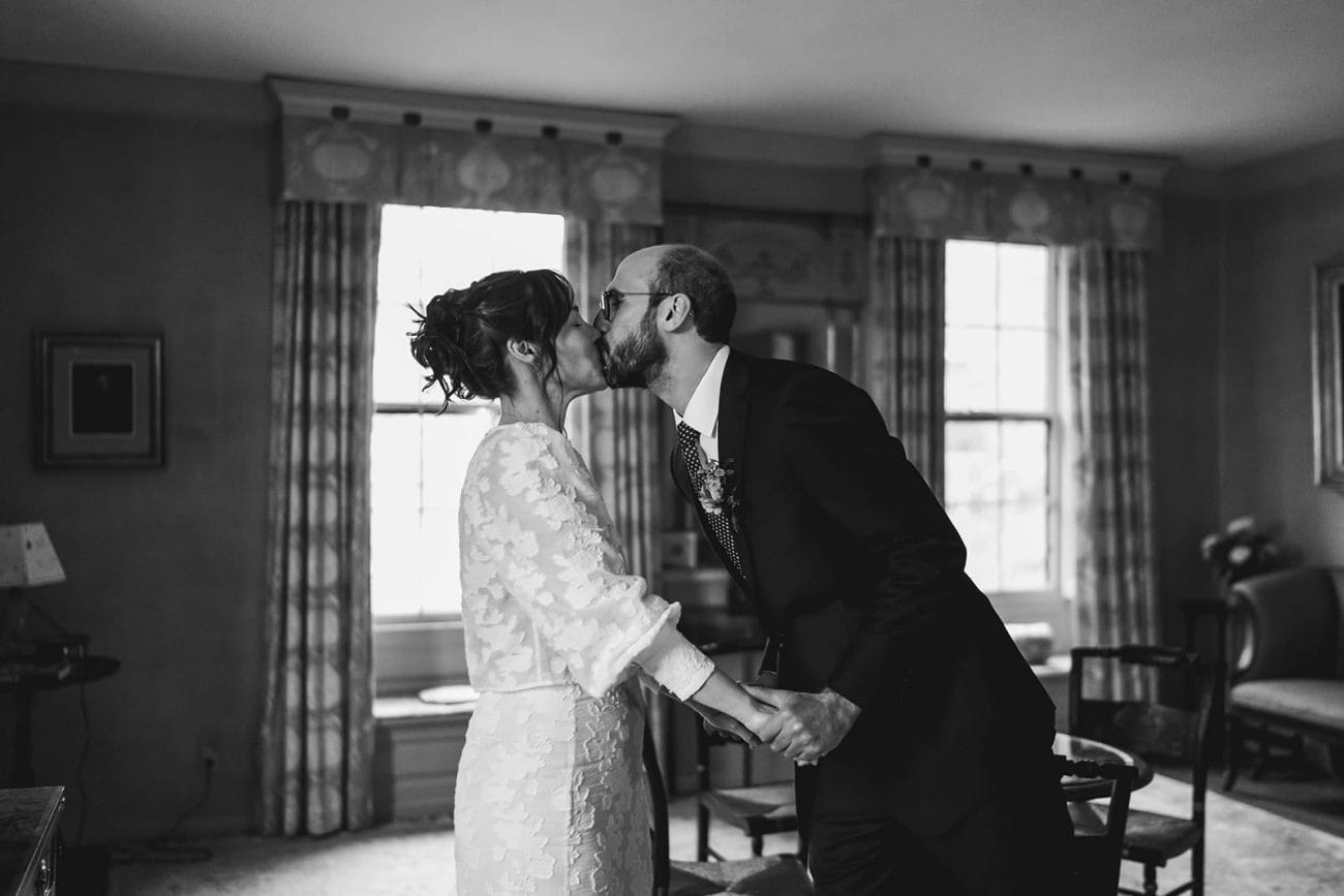A documentary photograph of a bride and groom seeing each other and sharing a kiss during their Loring Greenough House Wedding. 