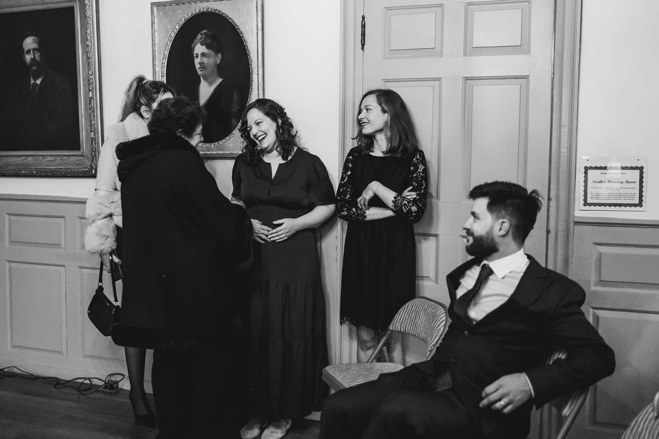A documentary photograph of guests talking and laughing during a Loring Greenough House Wedding. 