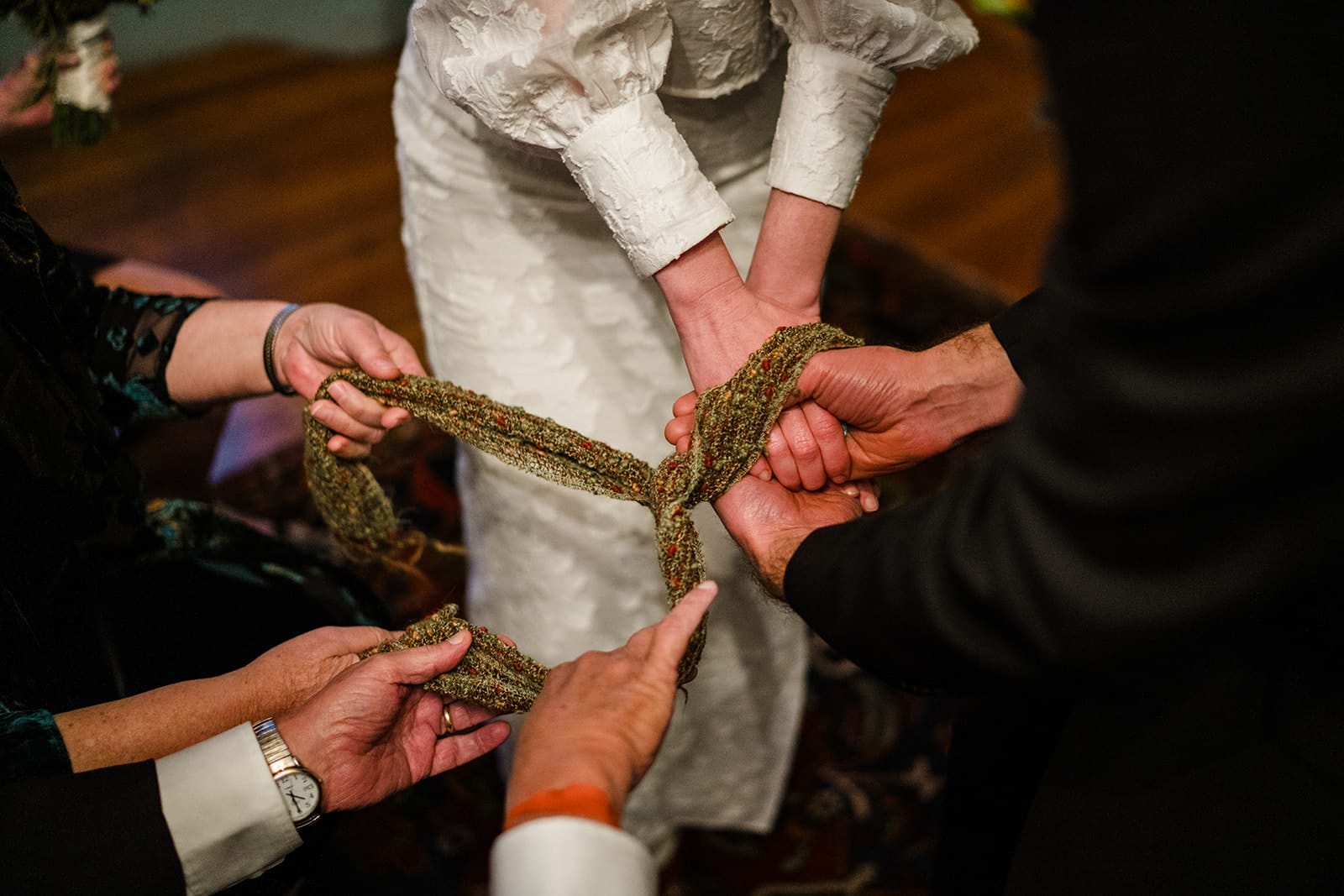 A documentary photograph of bride and groom doing a Celtic hand tying ceremony during their Loring Greenough House Wedding ceremony.  