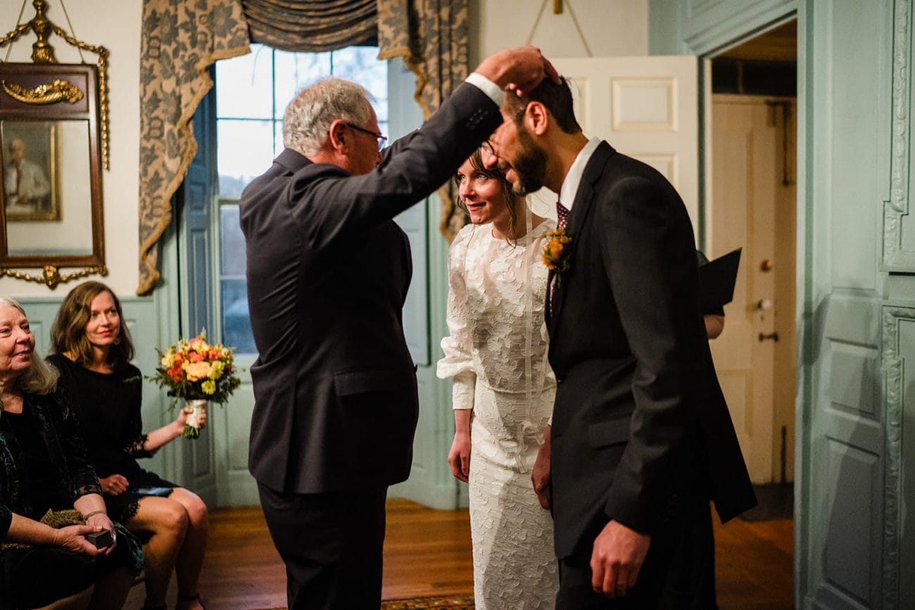 A documentary photograph of a bride and groom incorporating greek traditions during their Loring Greenough House Wedding ceremony.  