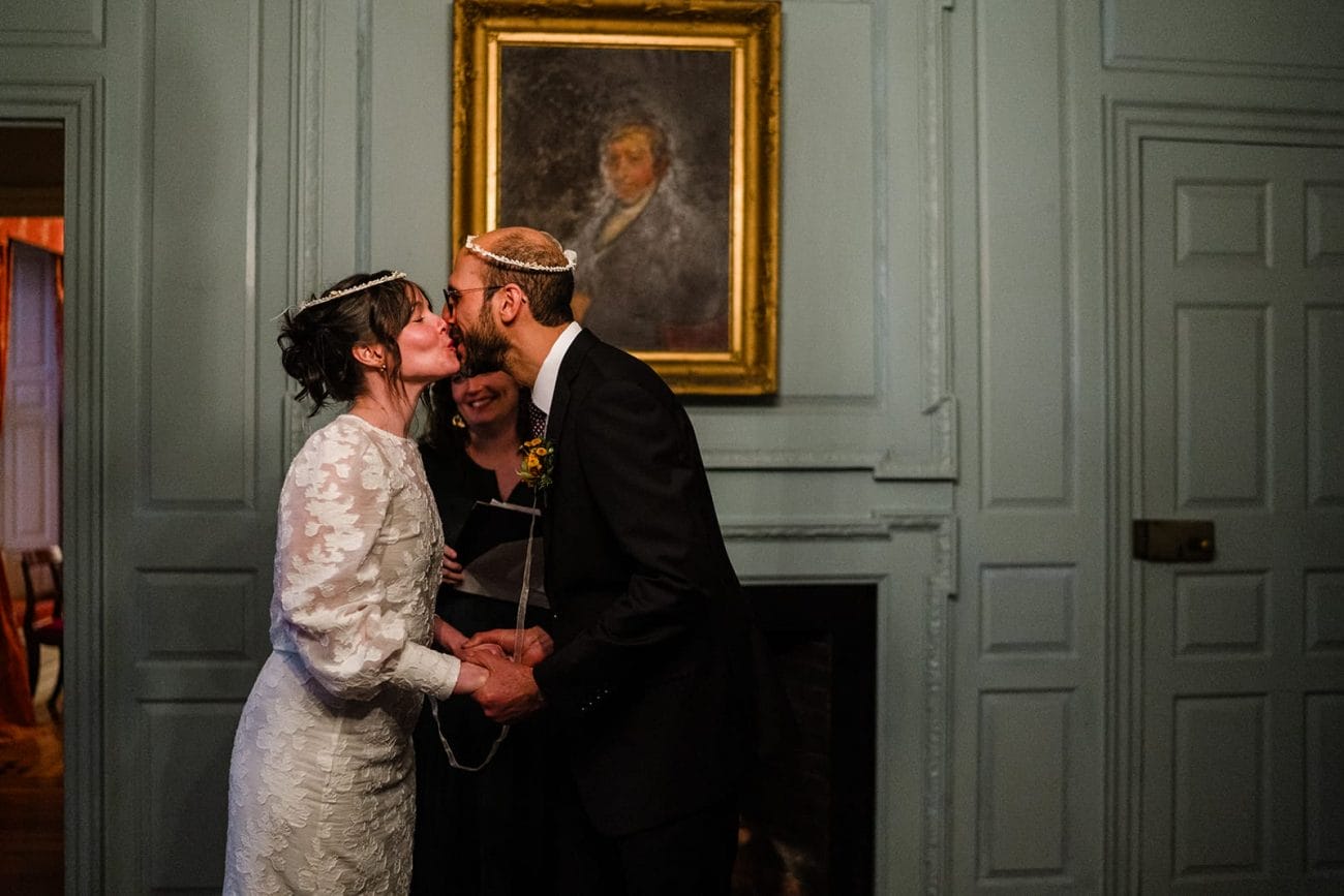 A documentary photograph of bride and groom kissing during their Loring Greenough House Wedding ceremony.  