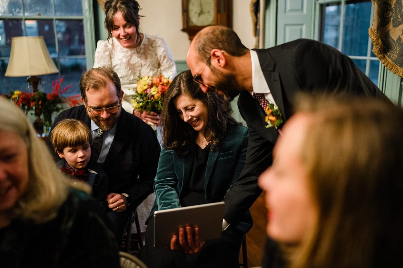 A documentary photograph of guests talking to zoom guests after a Loring Greenough House Wedding ceremony.  