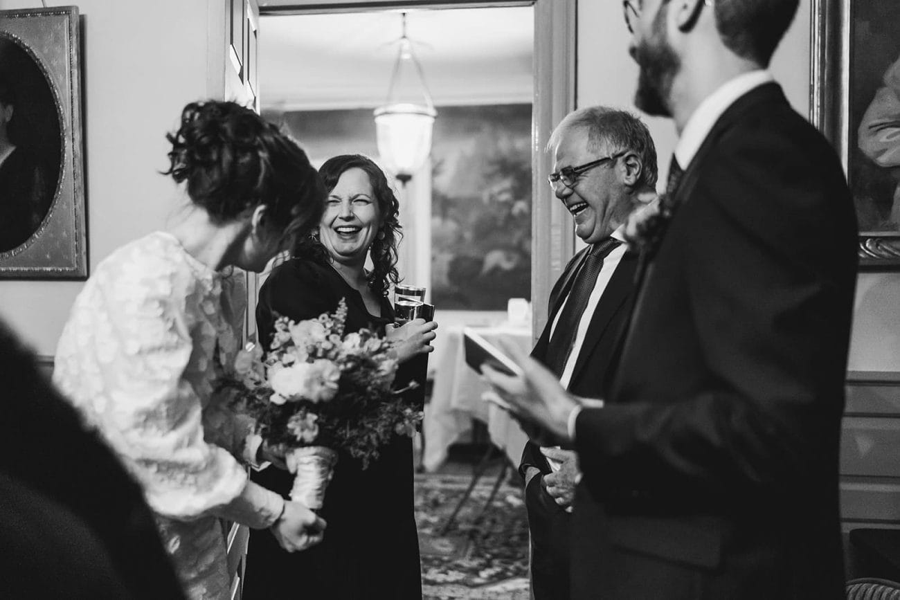 A documentary photograph of the bride talking and laughing with guests during their Loring Greenough House Wedding.  