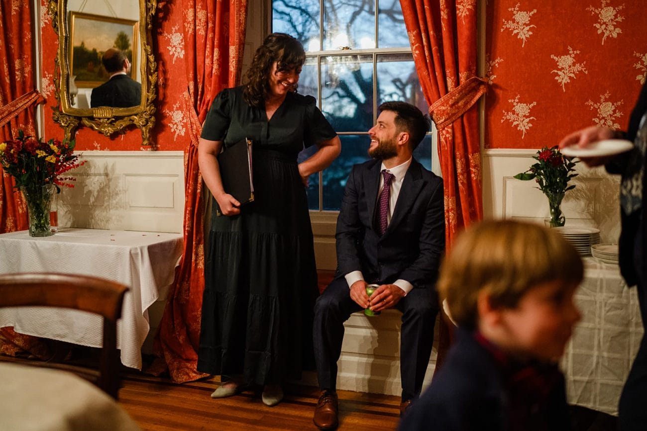 A documentary photograph of guests talking and laughing during a Loring Greenough House Wedding.  