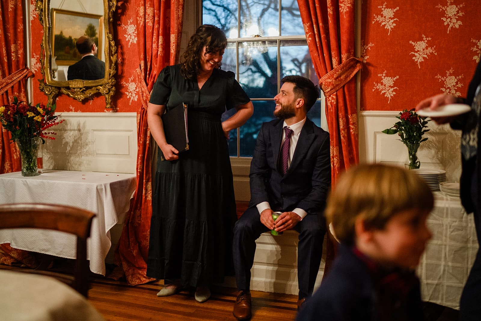 A documentary photograph of guests talking and laughing during a Loring Greenough House Wedding.  