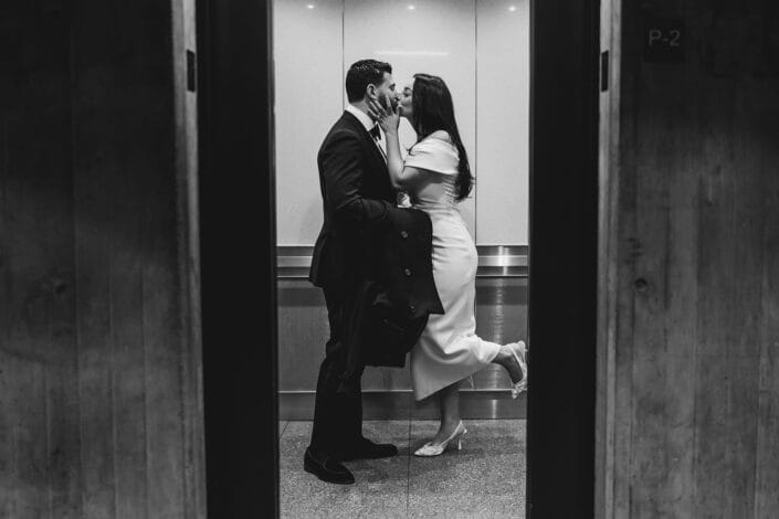 A documentary photograph of a bride and groom kissing in the elevator after their Boston City Hall ceremony.