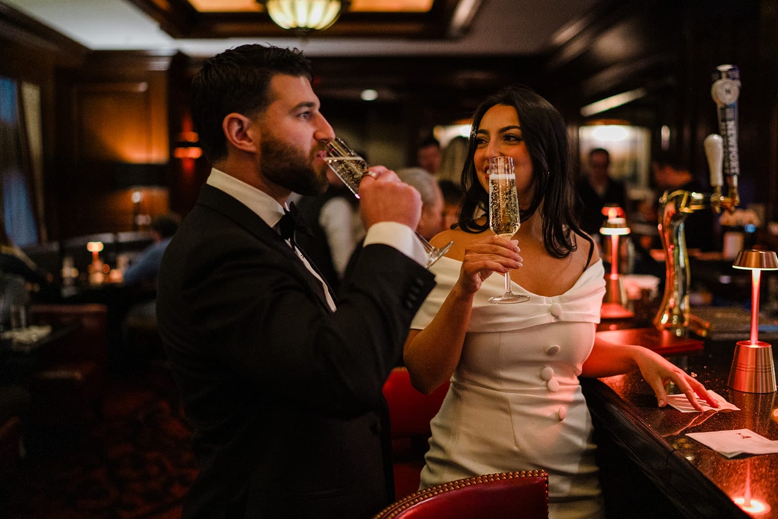 A documentary photograph of a bride and groom having champagne at The Dark Bar before their intimate wedding at Mooo.... Seaport.