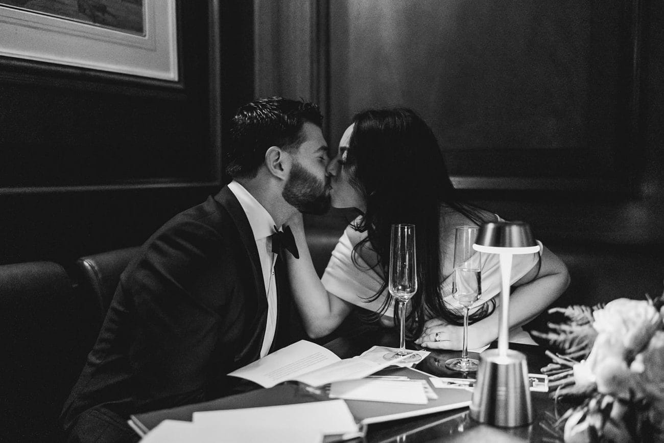 A documentary photograph of a bride and groom kissing at The Dark Bar before their intimate wedding at Mooo.... Seaport.