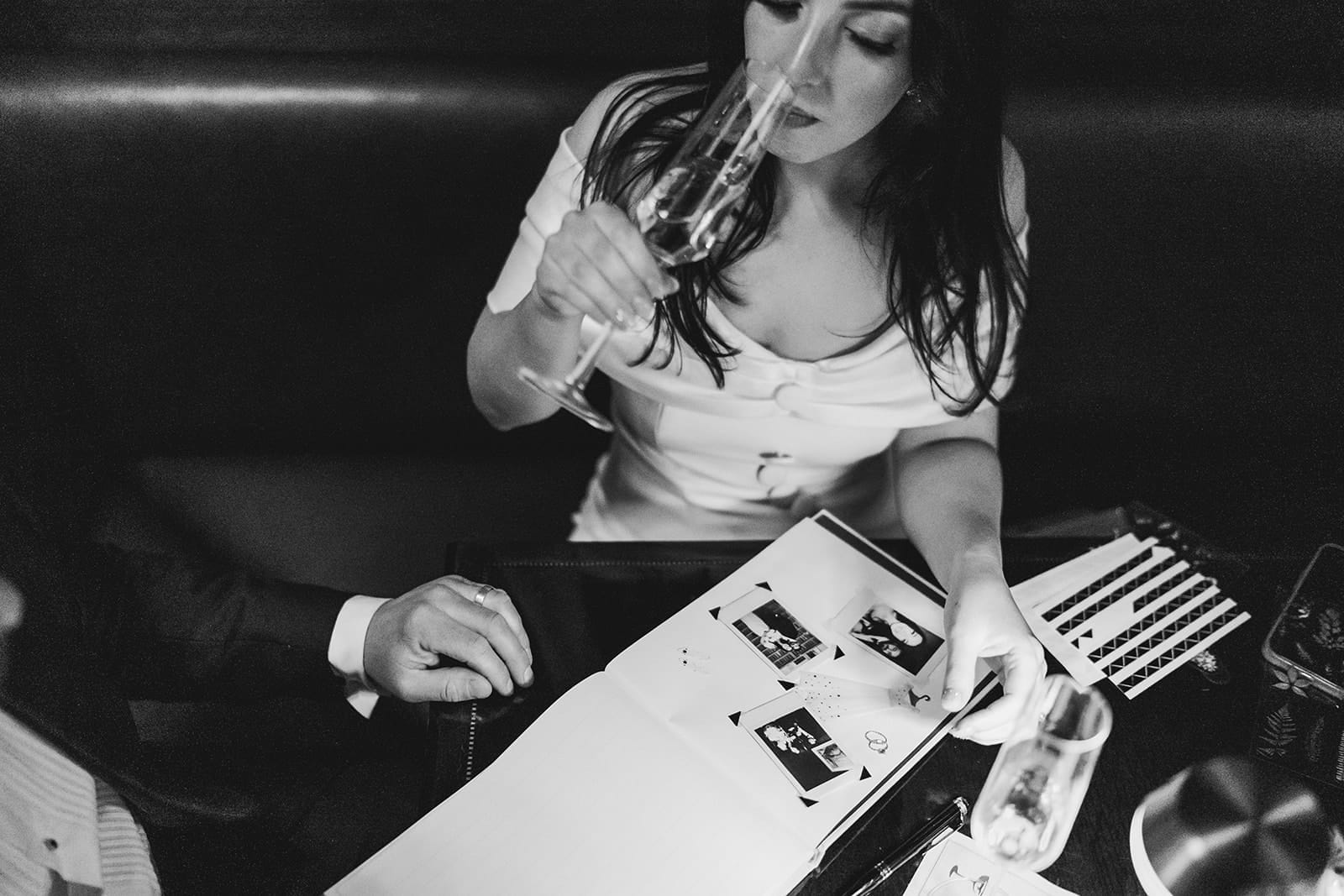 A documentary photograph of a bride and groom creating a guest book at The Dark Bar before their wedding celebration at Mooo.... Seaport.