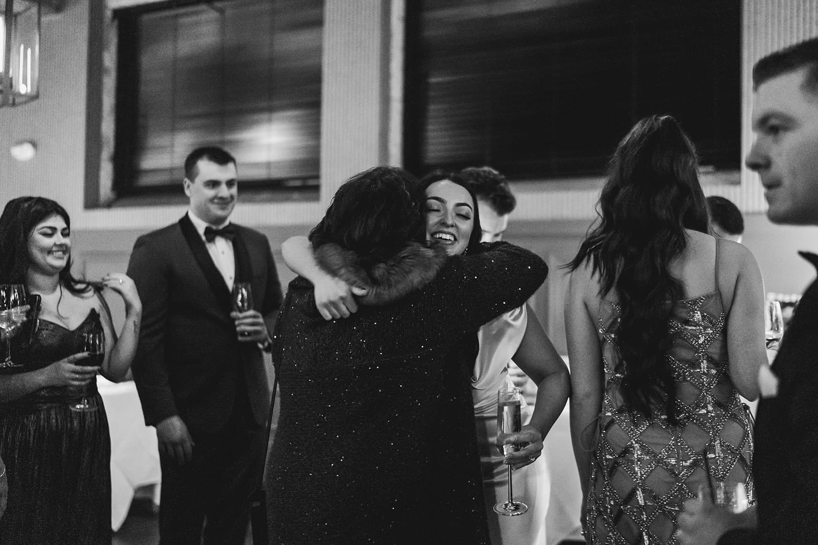A documentary photograph of a bride hugging her friends during their intimate wedding at Mooo.... Seaport.