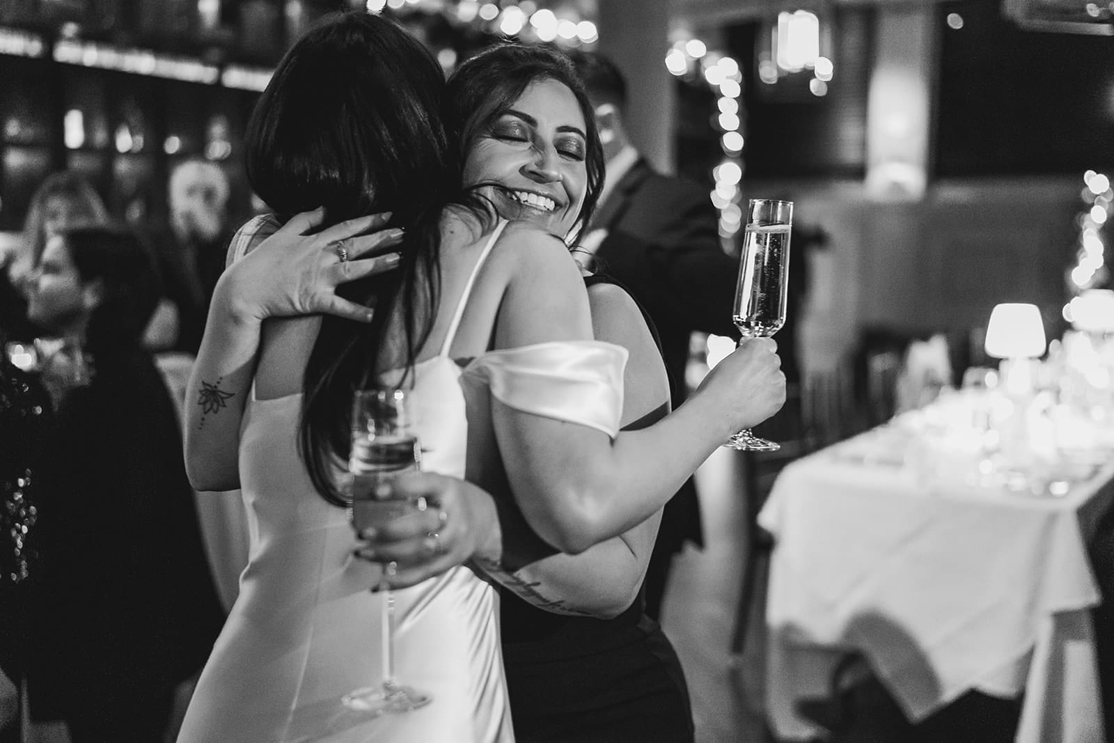 A documentary photograph of a bride hugging her sister during their wedding celebration at Mooo.... Seaport.