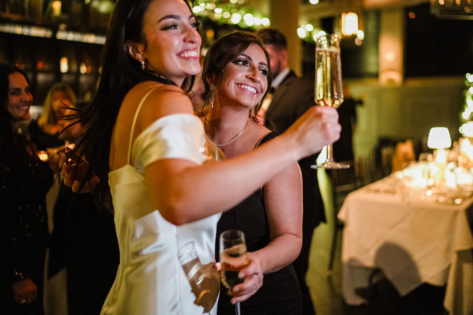 A documentary photograph of a joyful bride with her sister during their wedding celebration at Mooo.... Seaport.