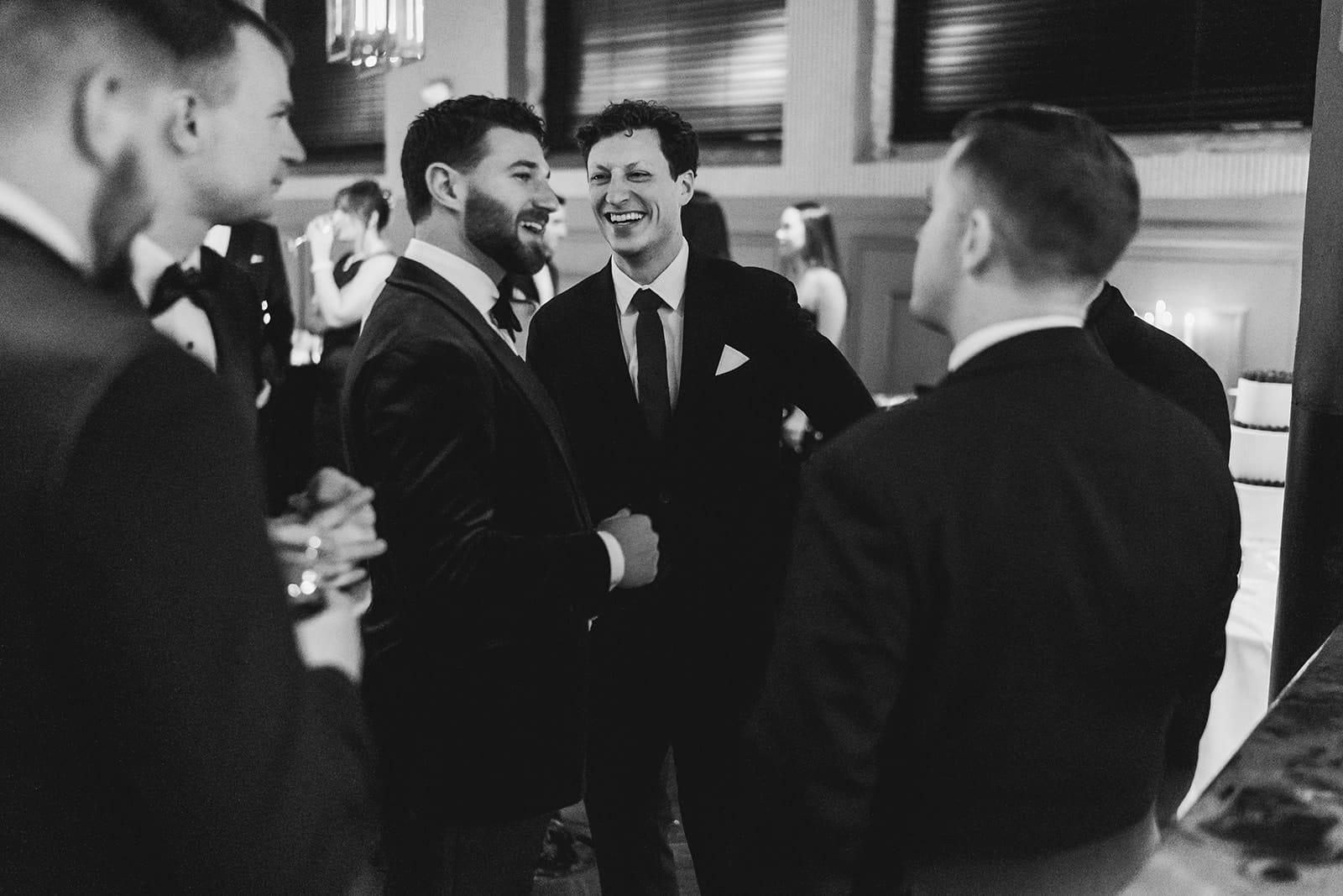 A documentary photograph of a groom laughing with friends during their wedding celebration at Mooo.... Seaport.