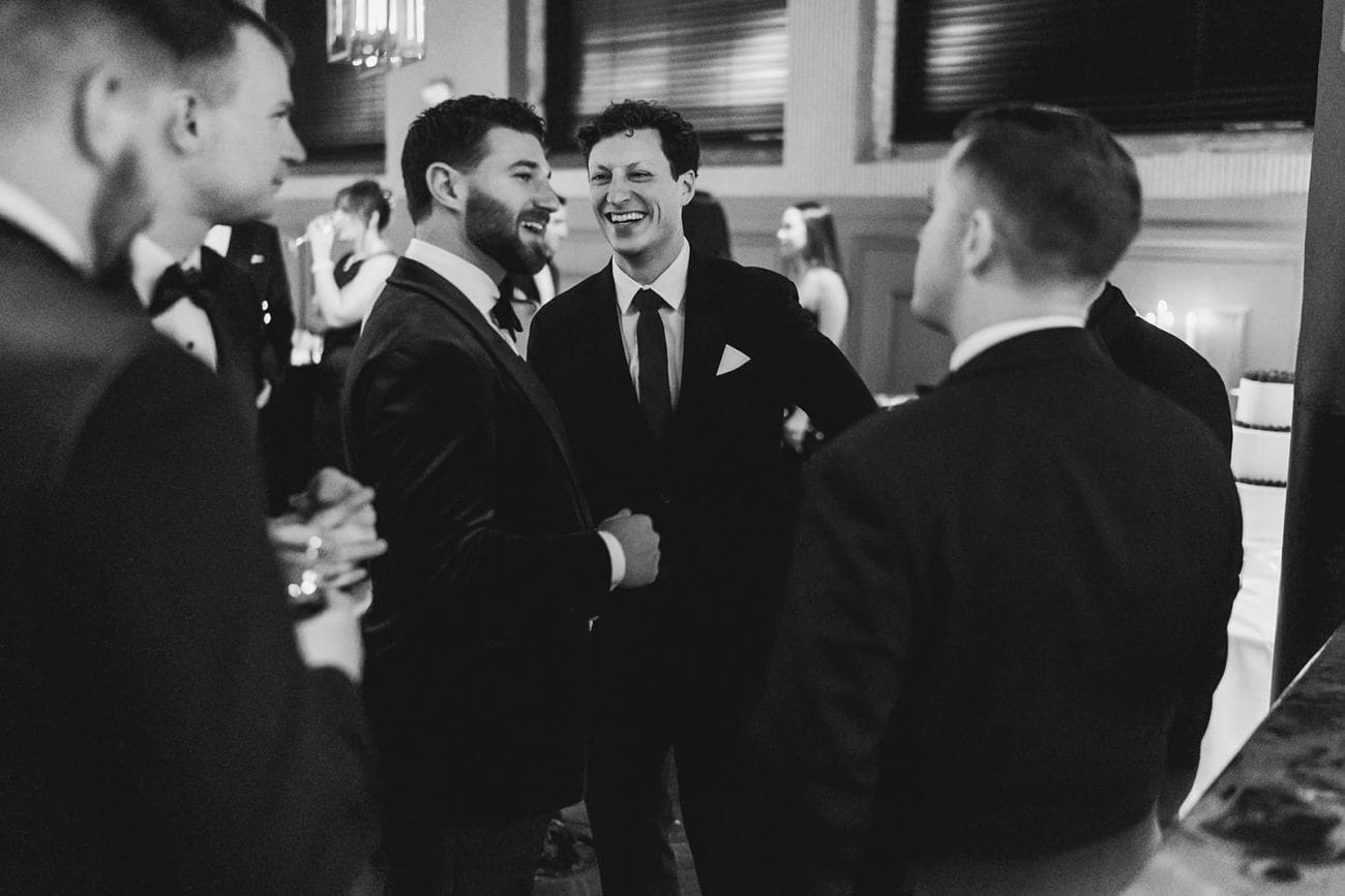 A documentary photograph of a groom laughing with friends during their wedding celebration at Mooo.... Seaport.