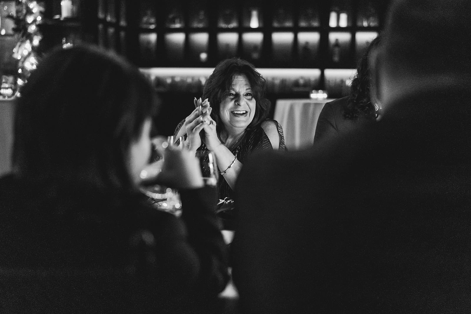 A documentary photograph of a guest talking at dinner during their wedding celebration at Mooo.... Seaport.