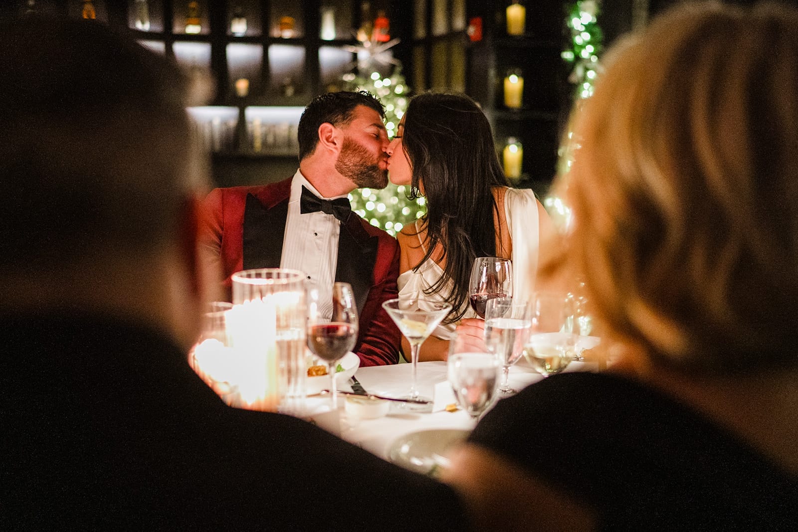 A documentary photograph of a bride and groom kissing at the table during their intimate wedding at Mooo.... Seaport.