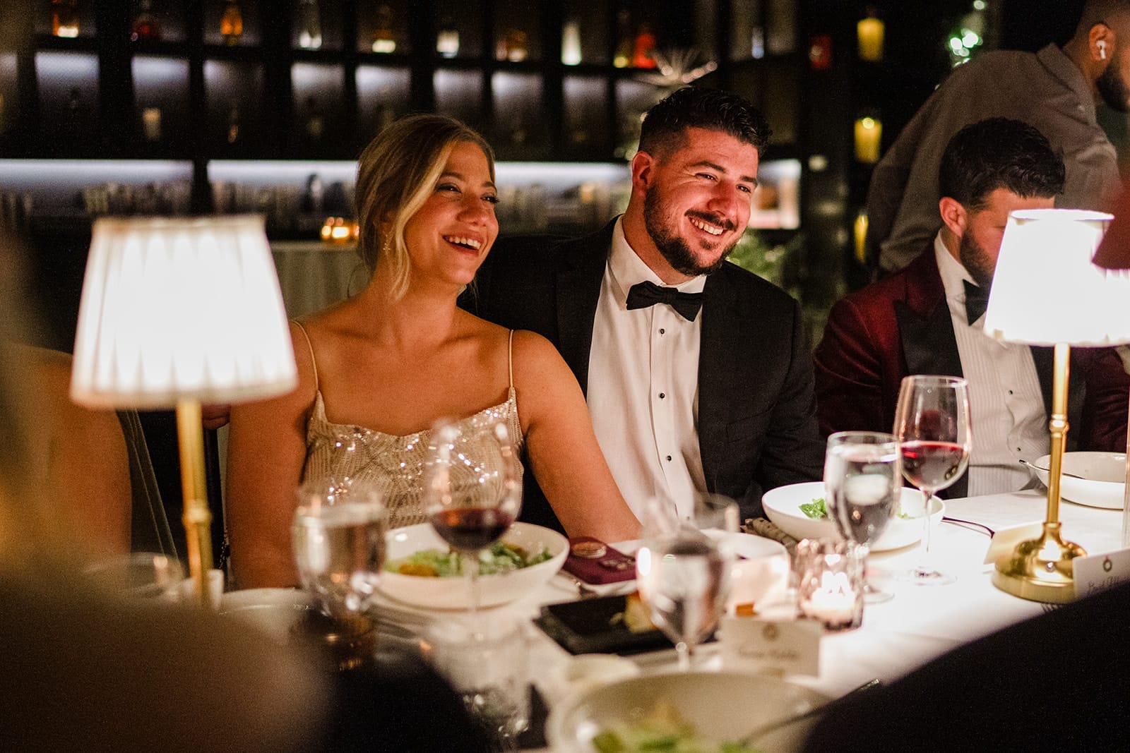 A documentary photograph of a couple laughing at the toasts during a wedding celebration at Mooo.... Seaport.