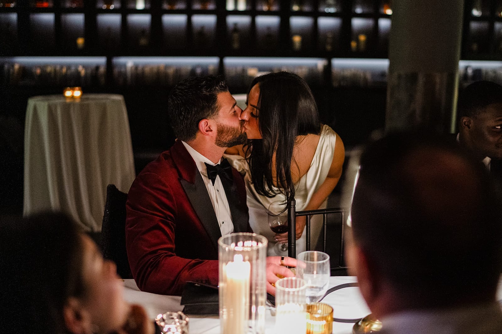 A documentary photograph of a bride and groom kissing at dinner during their intimate wedding at Mooo.... Seaport.