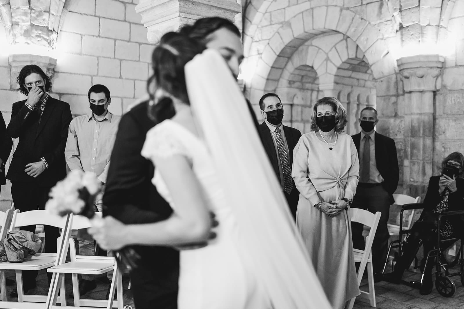 A documentary photograph of a bride hugging her brother at the top of the aisle during her intimate Worcester Art Museum Wedding