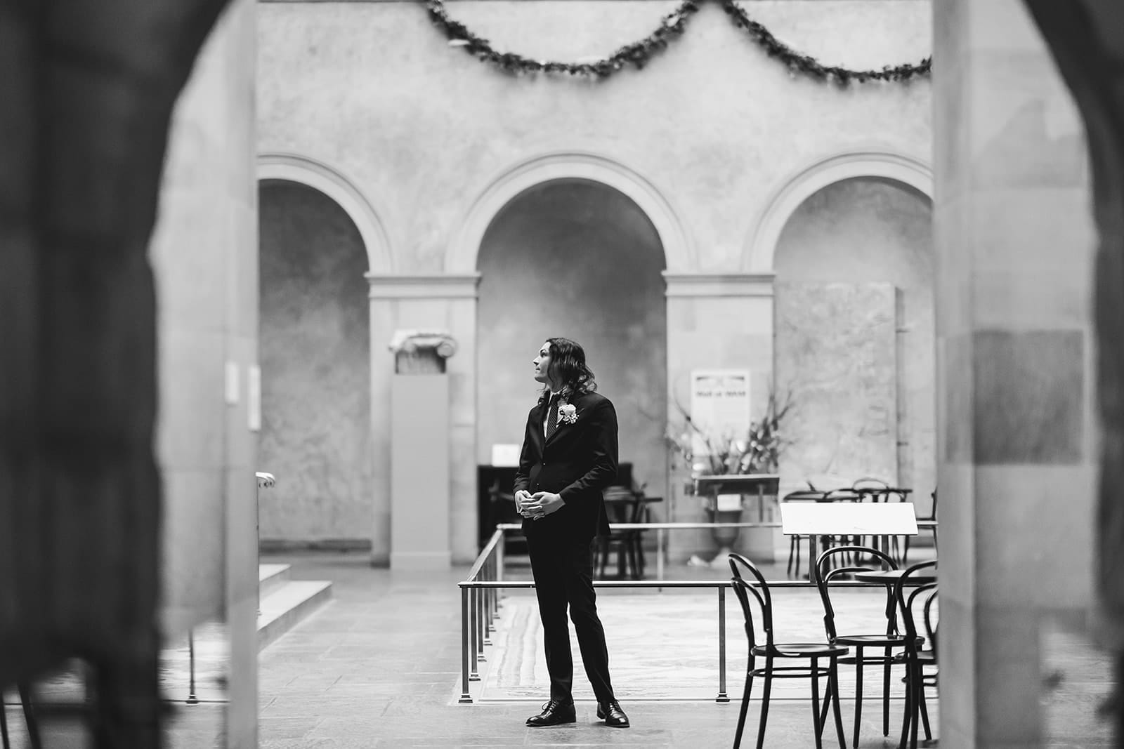 A documentary photograph of a groom waiting for his bride to come down the stairs during their intimate Worcester Art Museum Wedding