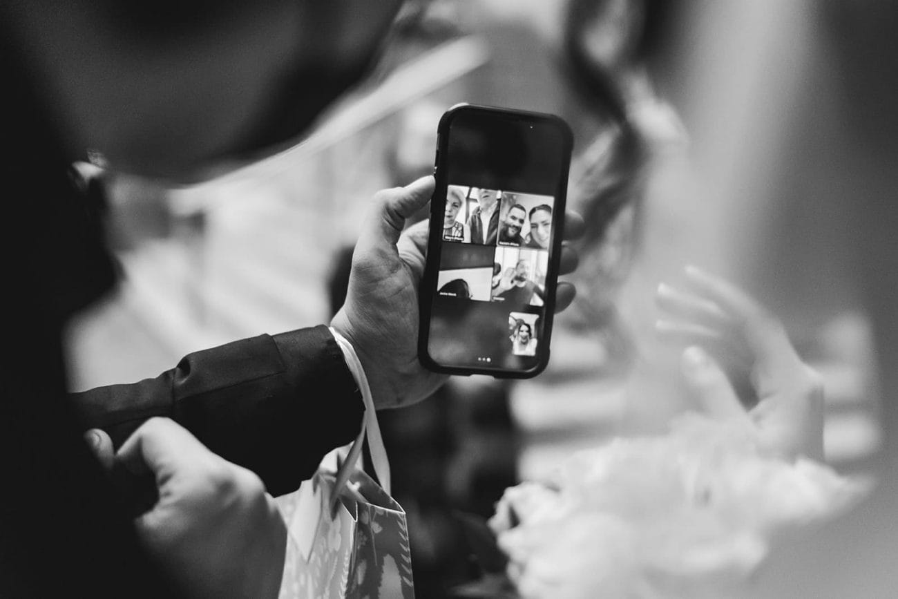 A documentary photograph of a bride and groom saying hi to family on zoom during their intimate Worcester Art Museum Wedding 