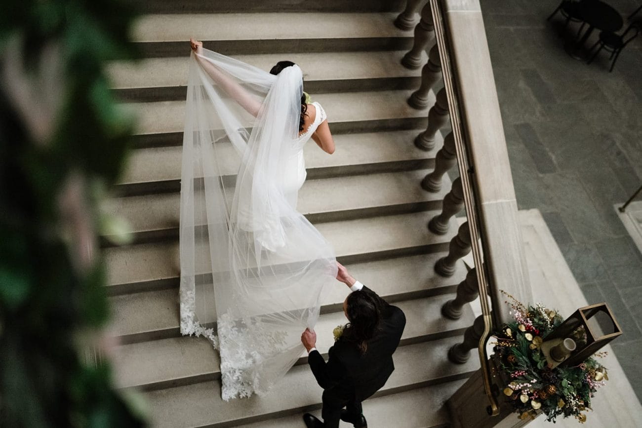 A documentary photograph of a bride and groom walking upstairs to the art galleries during their intimate Worcester Art Museum Wedding 