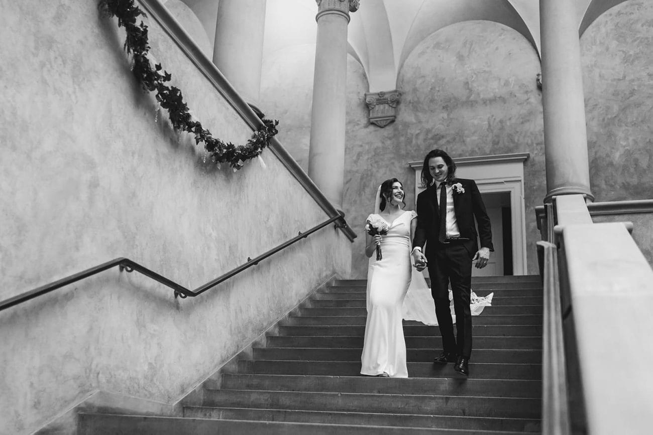 A documentary photograph of a bride and groom walking down the stairs during their intimate Worcester Art Museum Wedding 