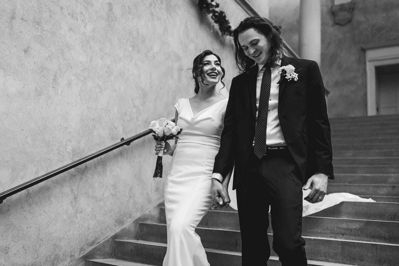 A documentary photograph of a bride and groom walking down the stairs during their intimate Worcester Art Museum Wedding 