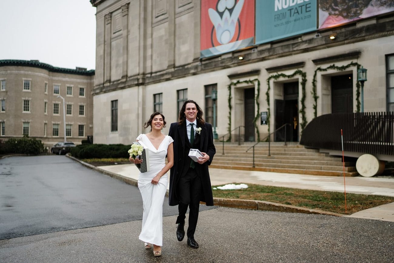 A documentary photograph of a bride and groom heading outside  during their intimate Worcester Art Museum Wedding 