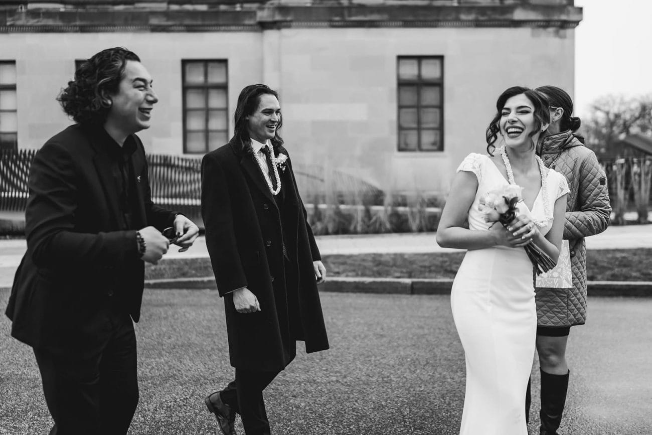 A documentary photograph of a bride and groom laughing with family outside  during their intimate Worcester Art Museum Wedding 