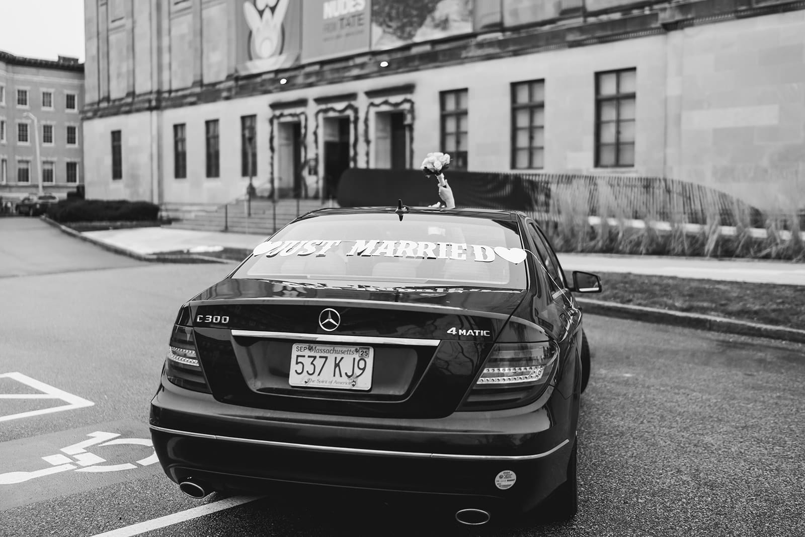 A documentary photograph of a bride and groom leaving in their car after their intimate Worcester Art Museum Wedding