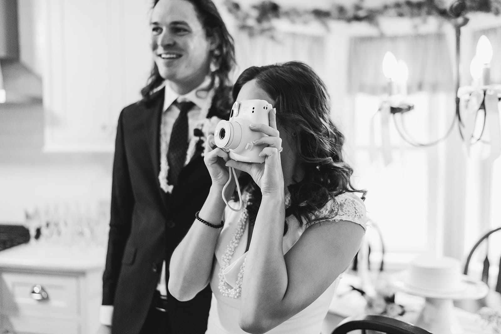 A documentary photograph of a bride taking a photograph during their in home celebration after their intimate Worcester Art Museum Wedding ceremony