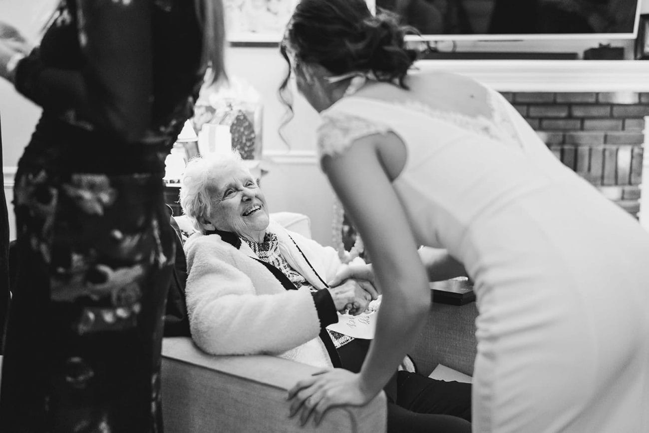 A documentary photograph of a bride talking with the groom's grandma during their in home celebration after their intimate Worcester Art Museum Wedding ceremony