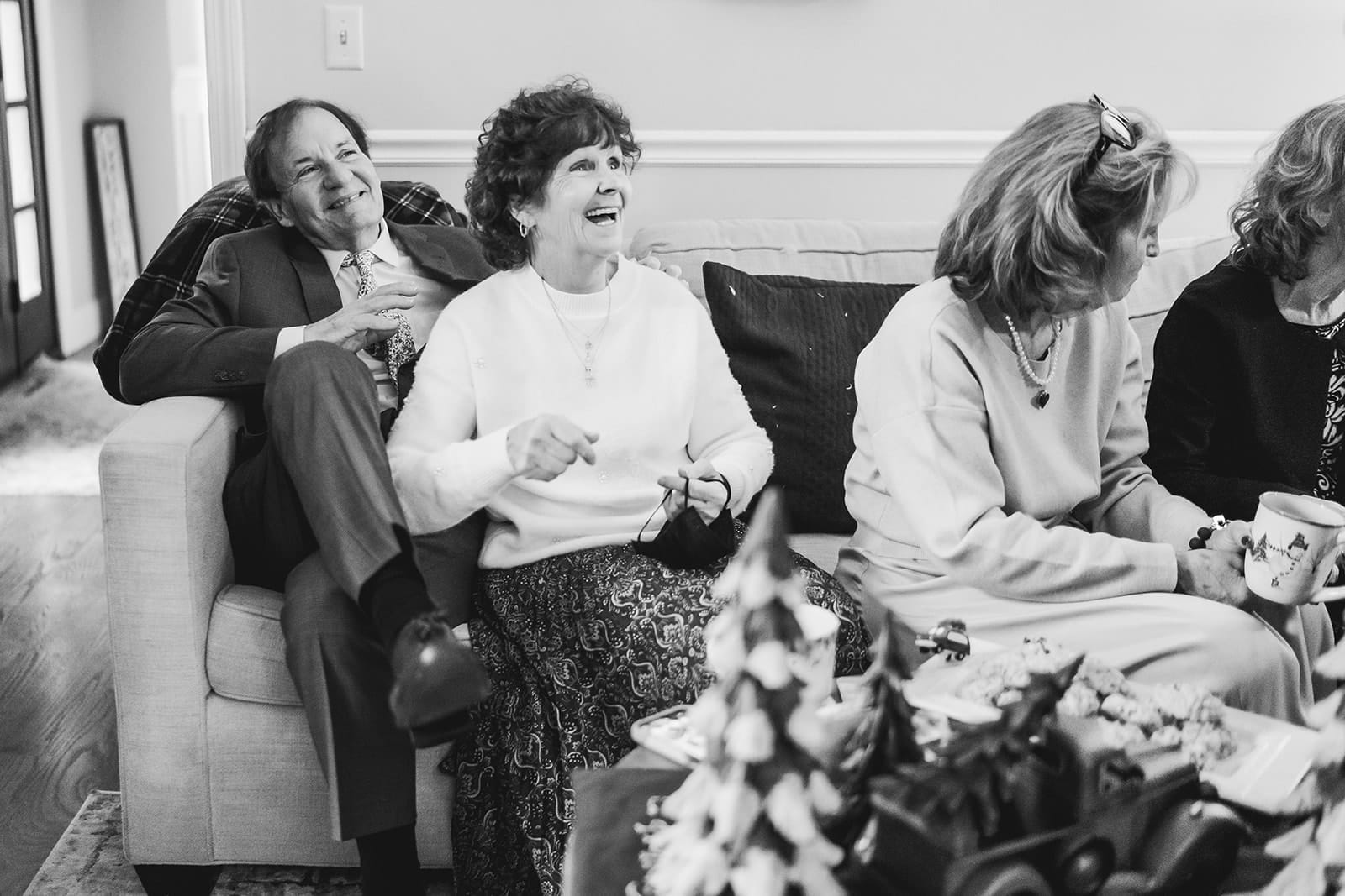 A documentary photograph of guests laughing during a in home celebration after their intimate Worcester Art Museum Wedding ceremony