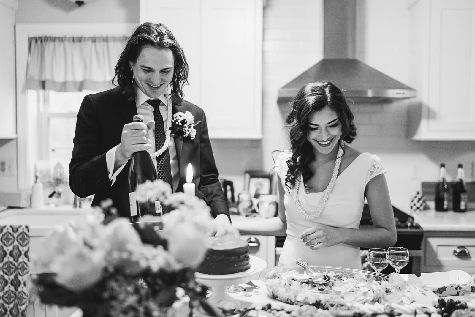 A documentary photograph of a bride and groom laughing in the kitchen during a in home celebration after their intimate Worcester Art Museum Wedding ceremony