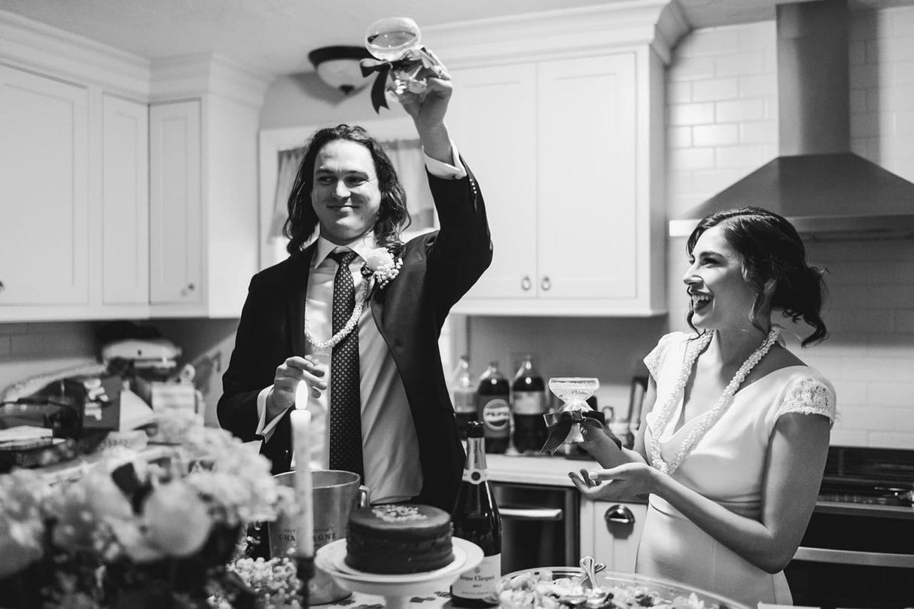 A documentary photograph of a bride and groom laughing in the kitchen during a in home celebration after their intimate Worcester Art Museum Wedding ceremony