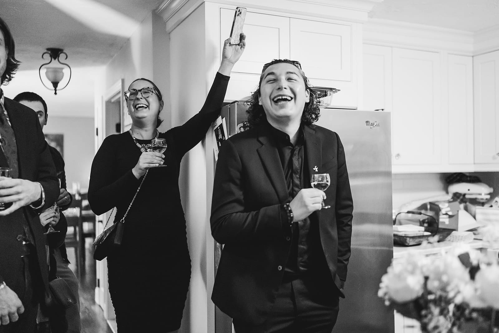 A documentary photograph of a guests laughing during a in home celebration after their intimate Worcester Art Museum Wedding ceremony
