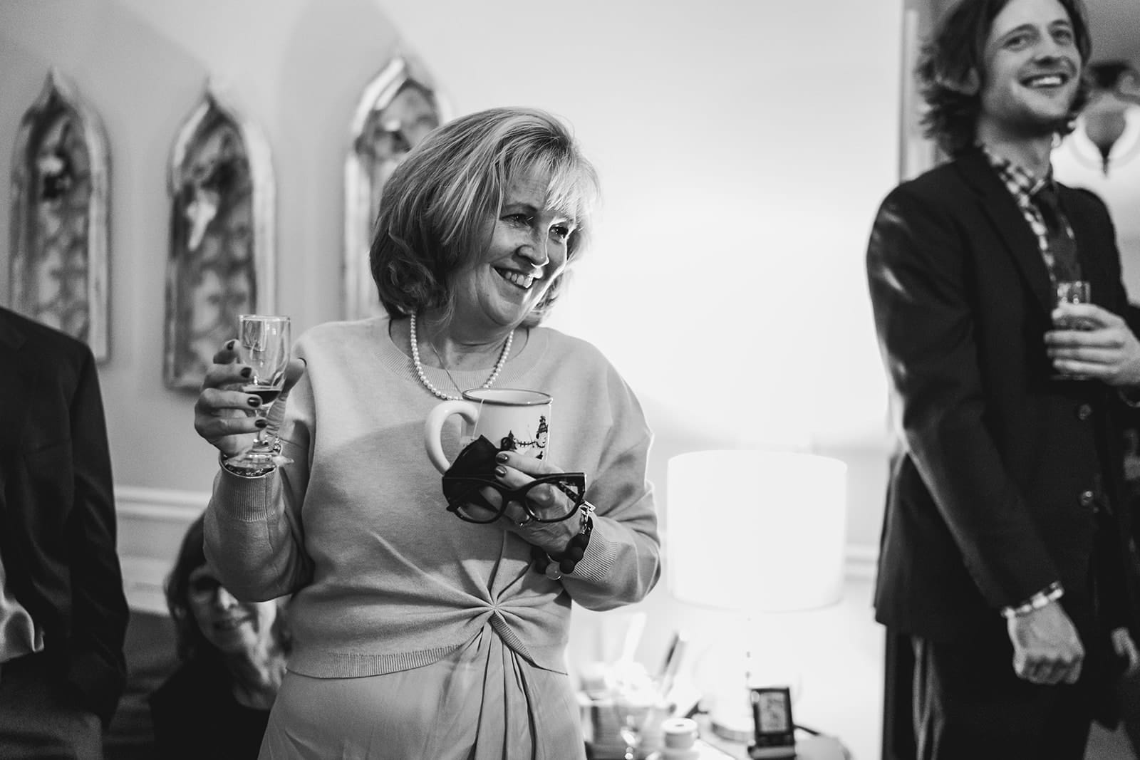 A documentary photograph of guests laughing during a in home celebration after their intimate Worcester Art Museum Wedding ceremony