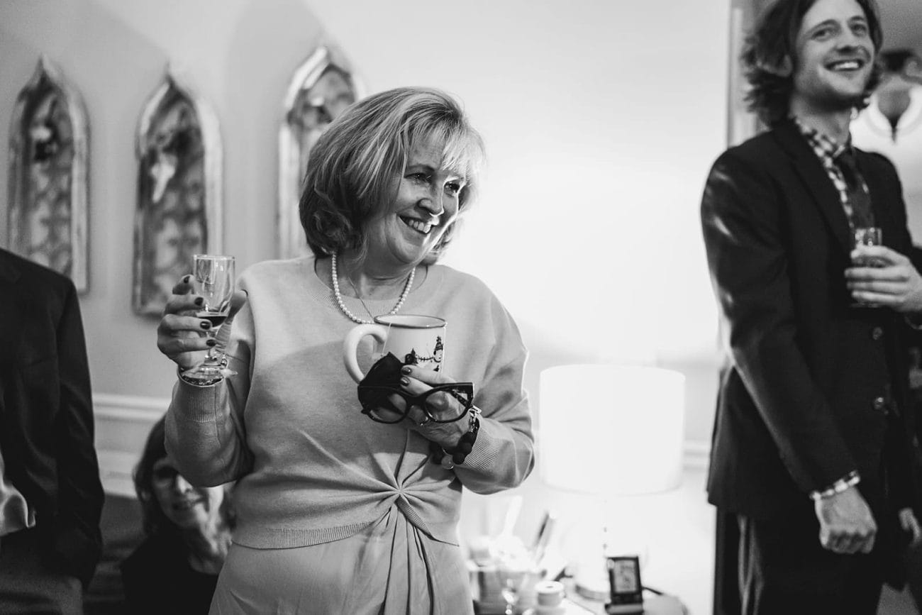 A documentary photograph of guests laughing during a in home celebration after their intimate Worcester Art Museum Wedding ceremony