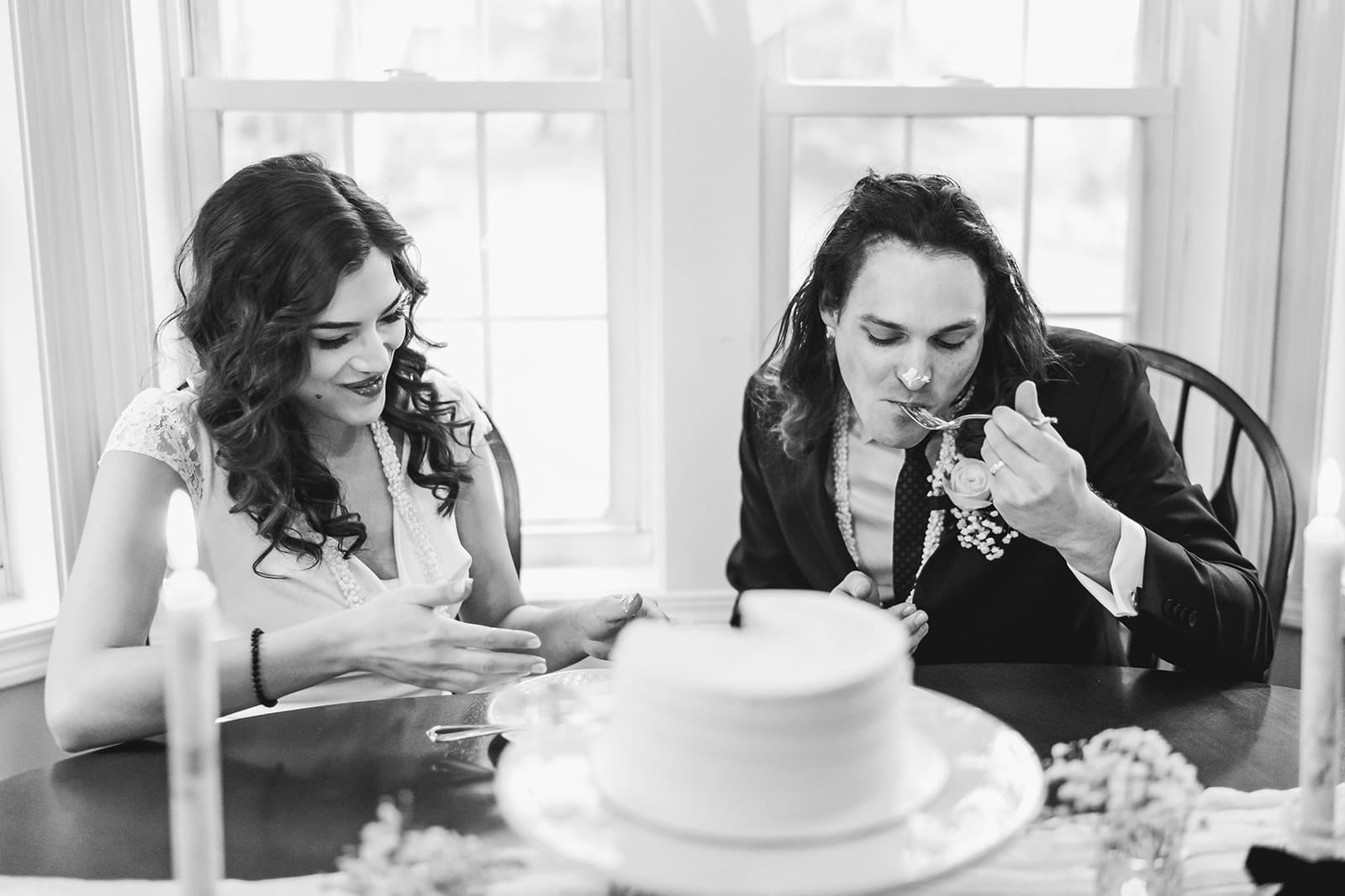A documentary photograph of a bride and groom having cake at the kitchen table during a in home celebration after their intimate Worcester Art Museum Wedding ceremony